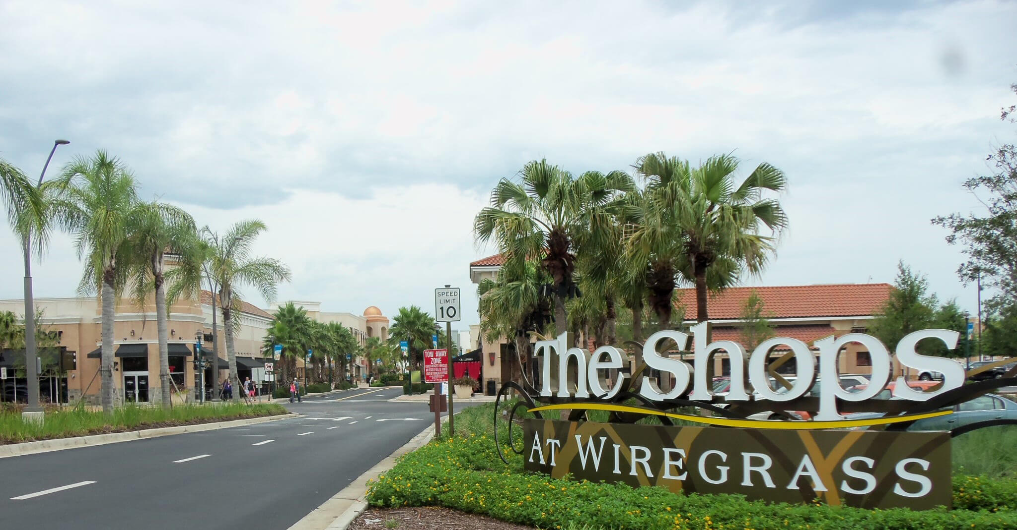 The Shops at Wiregrass mall entrance sign and palm-lined street in Wesley Chapel, Florida